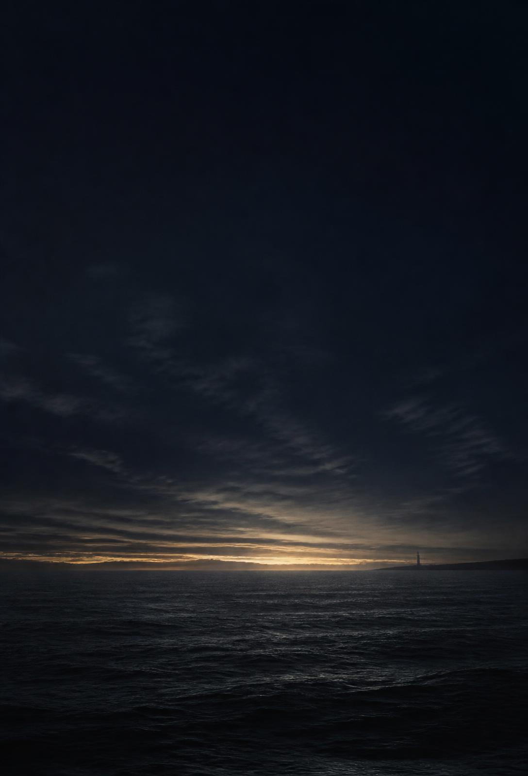 Oceano escuro diante da primeira luz no horizonte